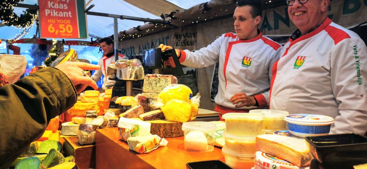 two cheese mongers selling gouda cheeses at noordermarkt amsterdam