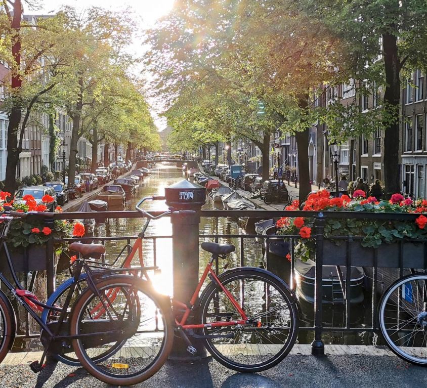 three bicycles parked by an amsterdam canal