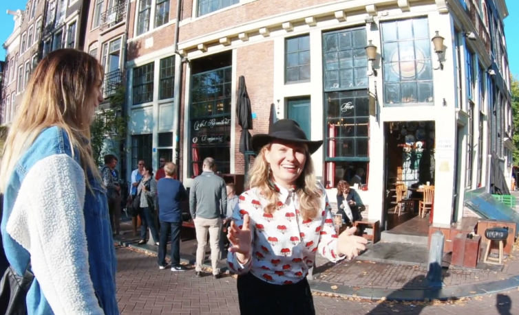 Tour guide sharing facts about Amsterdam with guest outside Cafe Papeneiland Amsterdam