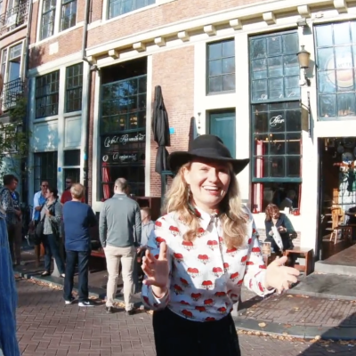 Tour guide sharing facts about Amsterdam with guest outside Cafe Papeneiland Amsterdam